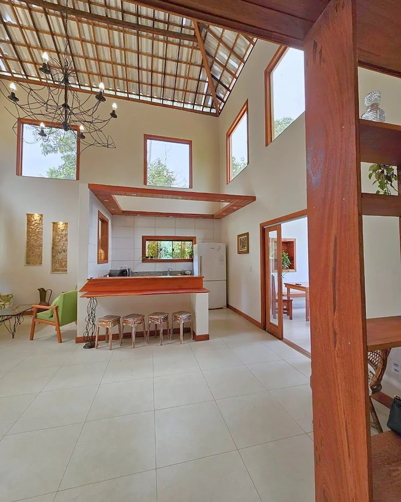 Sala integrada e cozinha sob o pé-direito alto de madeira